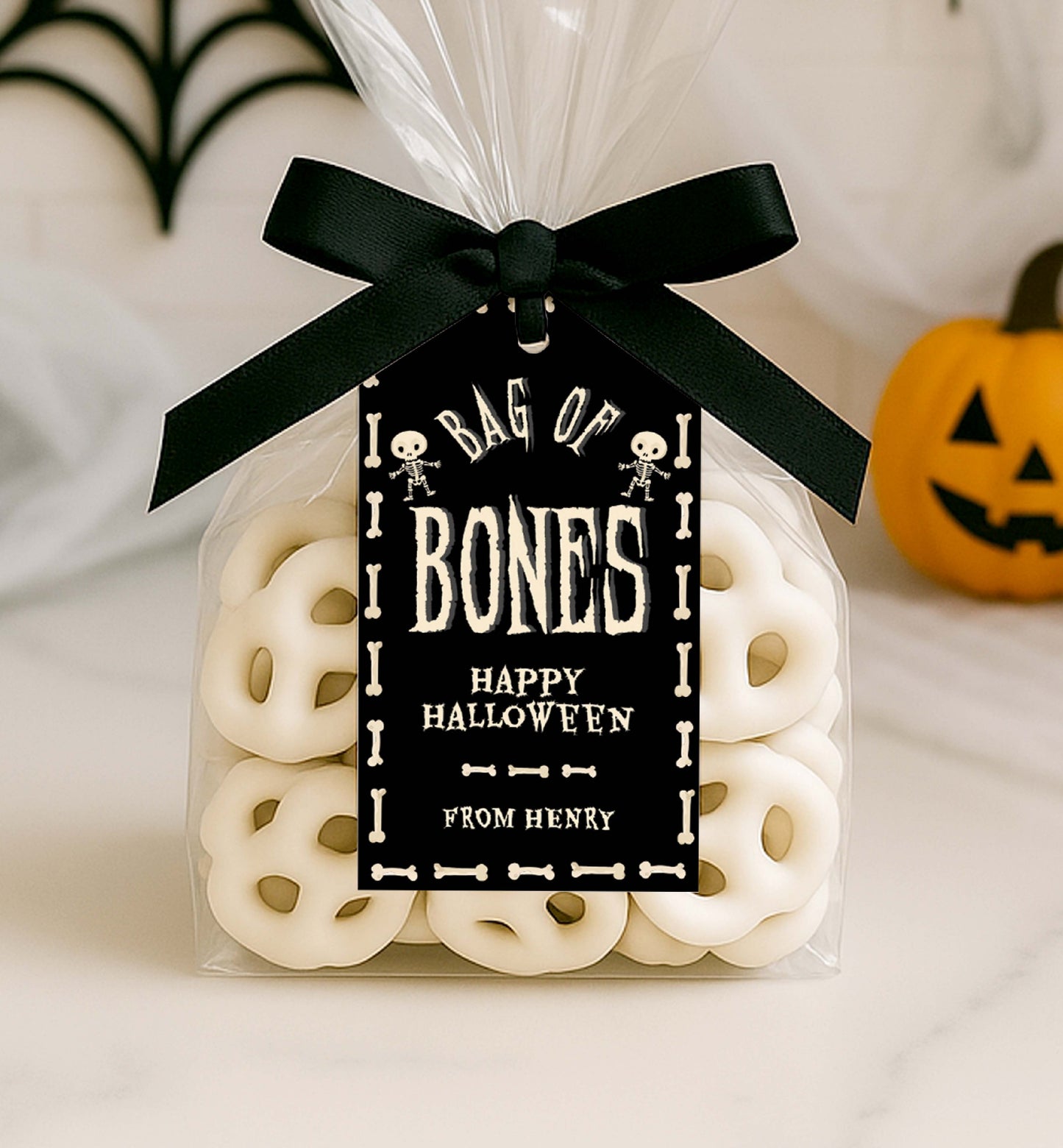 Halloween-themed treat bag with 'Bag of Bones' label and black ribbon, against a neutral background. Bag Of Bones Treat Tag, Skeleton Bones, Printable Halloween Favor Tags, Trick Or Treat Party Favors, Classroom Halloween Gift
