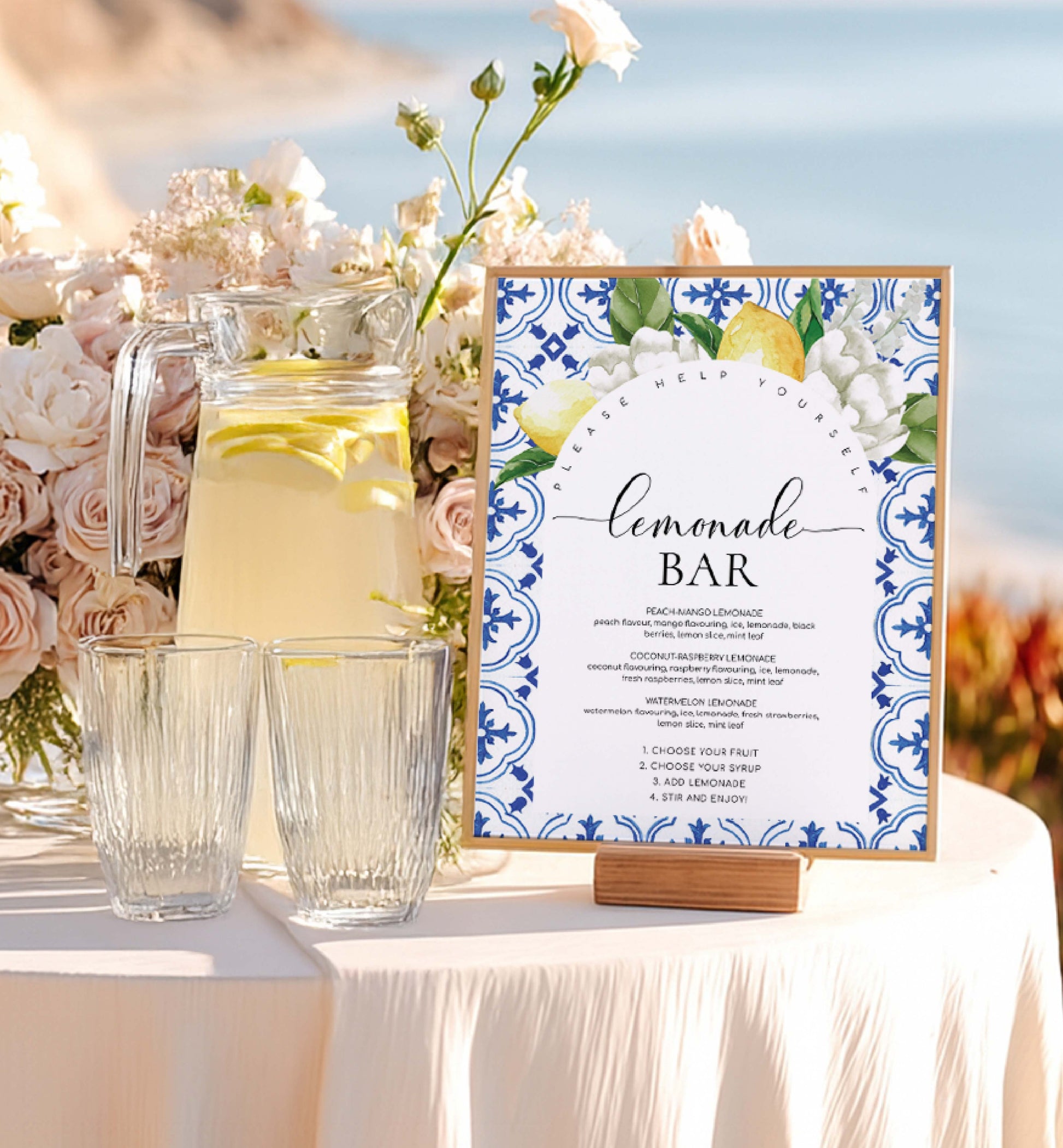 Lemonade stand with lemonade, glasses, and a decorative 'Lemonade Bar' sign against a scenic background. Printable Lemonade Bar Sign, Mediterranean Blue Tile Lemons, Editable Drinks Menu Sign, Mocktails Menu Sign, Signature Drinks Sign, The Med