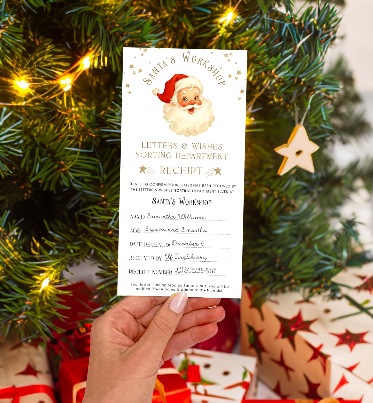 Hand holding a Santa Claus letter under a decorated Christmas tree with lights and ornaments. Printable Letter To Santa Receipt, Santa's Nice List Receipt, Letter From Santa's Workshop, North Pole Mail, Christmas Eve Box Santa Letter