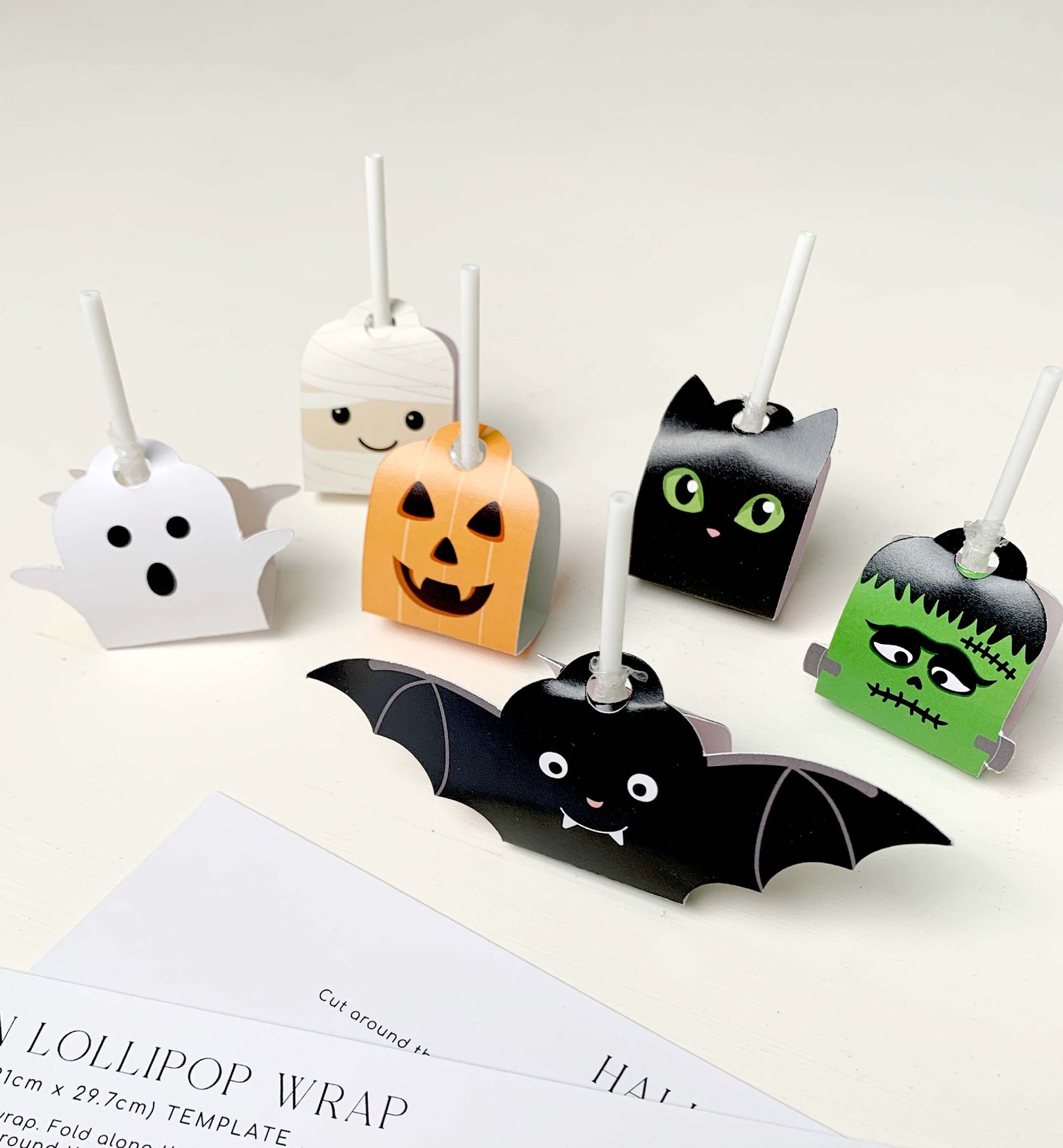 Halloween-themed lollipop wraps with ghost, pumpkin, bat, and Frankenstein designs on a white background. Printable Halloween Lollipop Tags Template, Halloween Trick or Treat Sucker Tag, Kids Classroom Halloween, Friends Halloween Gift