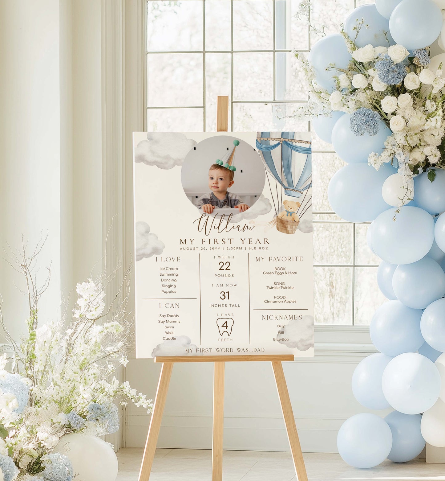 Decorative setup with a photo of a baby on a stand, balloons, and flowers in a room. Printable Baby Milestone Board, Teddy Bear Beary First Birthday, Baby's First Year Poster, 1st Birthday 12 Months Milestone Photo Banner Sign