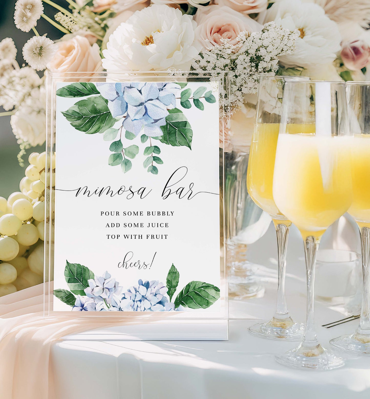 Mimosa bar setup with floral decorations and champagne glasses. Printable Mimosa Bar Sign and Juice Tags Template, Blue Hydrangea Boy Baby Shower Drinks Bar Menu Sign, Gender Neutral, Ferras Blossom