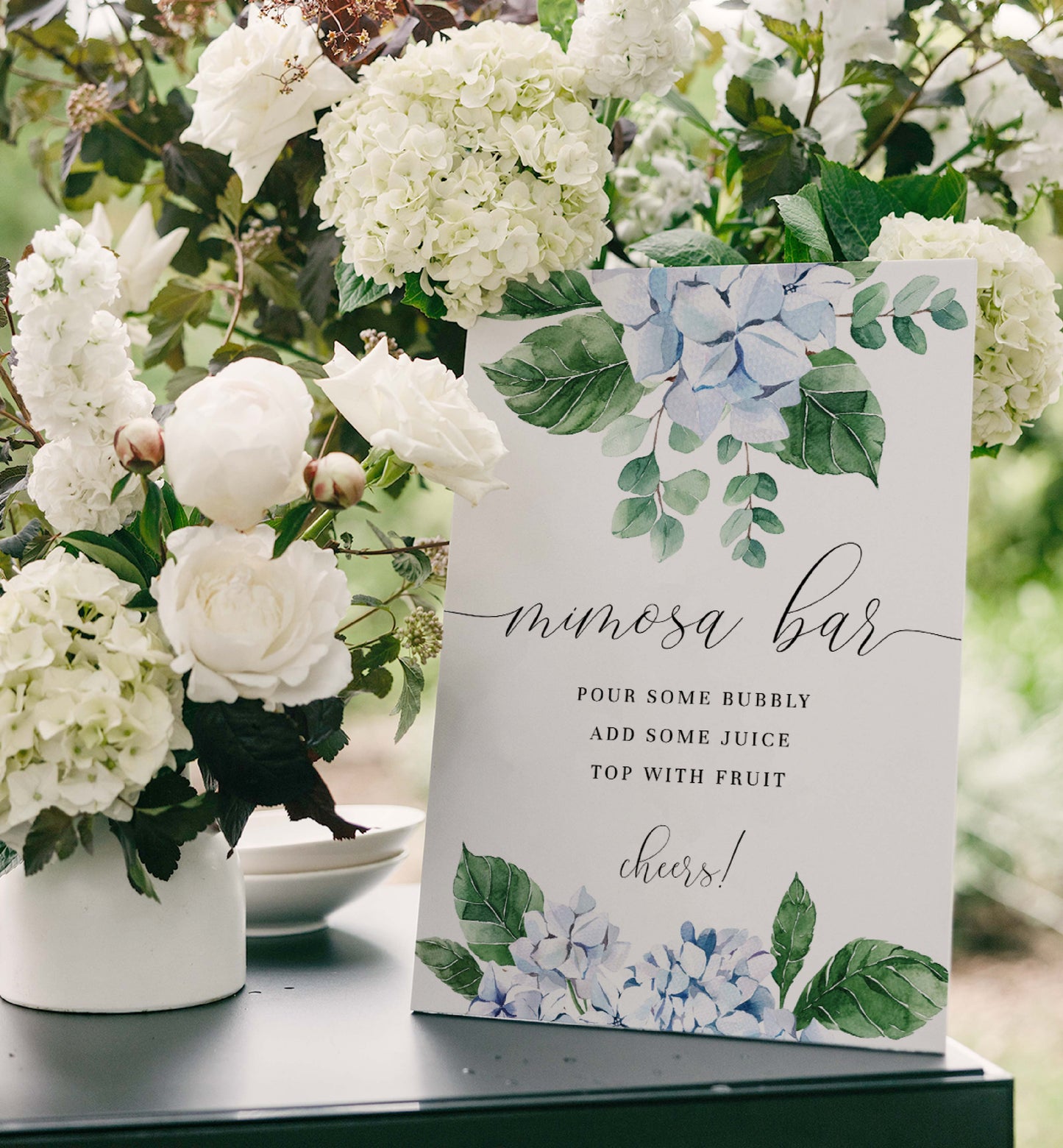 Mimosa bar sign with floral design next to white flowers. Printable Mimosa Bar Sign and Juice Tags Template, Blue Hydrangea Boy Baby Shower Drinks Bar Menu Sign, Gender Neutral, Ferras Blossom