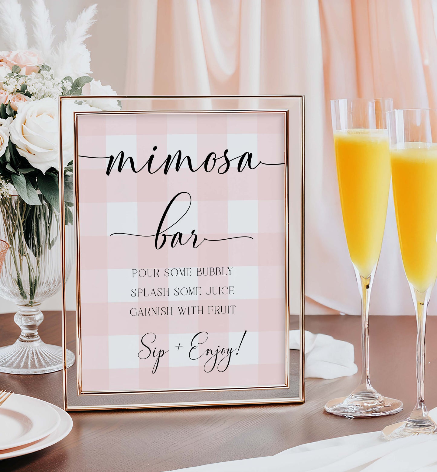 Framed 'mimosa bar' sign with two glasses of orange juice on a table. Printable Mimosa Bar Sign and Juice Tags, Pink Gingham Check, Girl Baby Shower Mom-osa Bar Sign, Baby Shower Mocktails Drinks Sign
