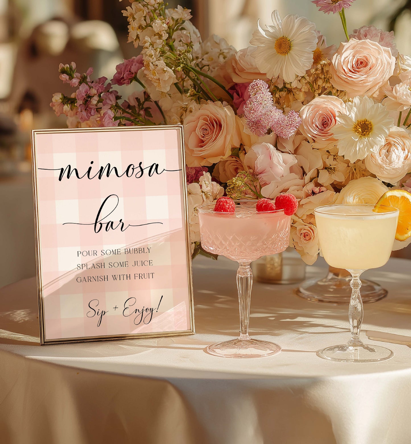 Mimosa bar setup with floral arrangement and sign on a table. Printable Mimosa Bar Sign and Juice Tags, Pink Gingham Check, Girl Baby Shower Mom-osa Bar Sign, Baby Shower Mocktails Drinks Sign