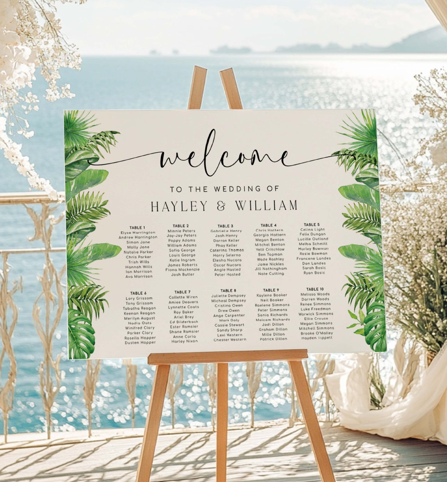 Wedding seating chart with tropical leaf design on an easel by a beach. Tropical Palm Wedding Table Plan, Printable Editable Seating Chart Template, Tropical Greenery Wedding Seating Plan Card, Nantucket Palm