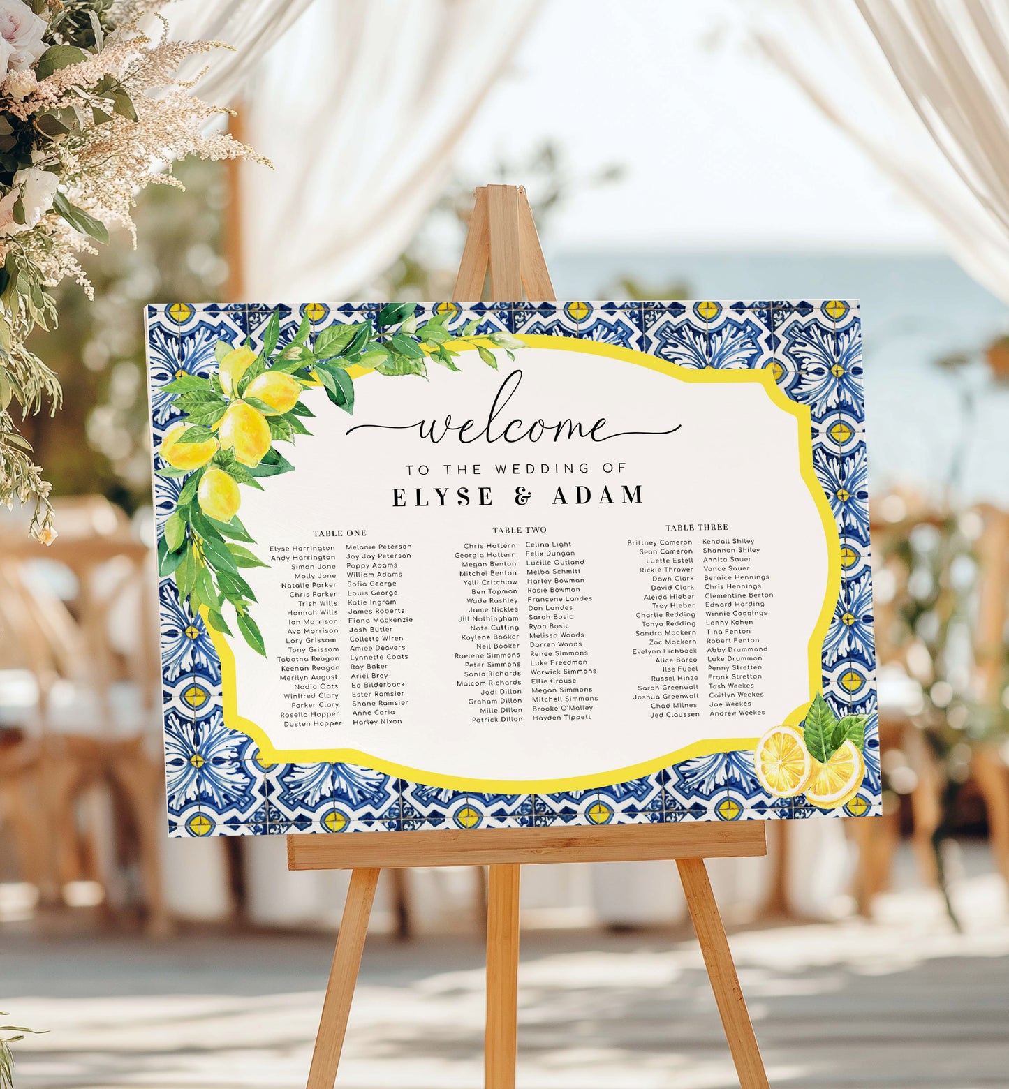 Wedding seating chart with decorative border on an easel.
Printable Wedding 3 Banquet Table Plan, Italian Theme, Positano Blue Tile Lemon Seating Chart, Seating Plan Poster, Guest List Seating Sign