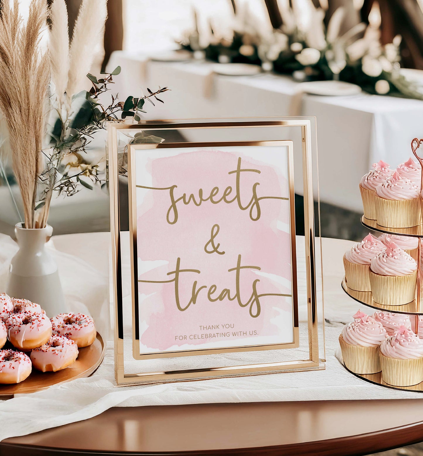 Decorative sign with 'sweets & treats' text in a gold frame, surrounded by pink donuts and cupcakes on a table. Sweets and Treats Favors Sign, Pink Watercolour Printable Favours Sign, Gold Foil, Bridal and Baby Favors Shower Sign, Wedding Favors Sign