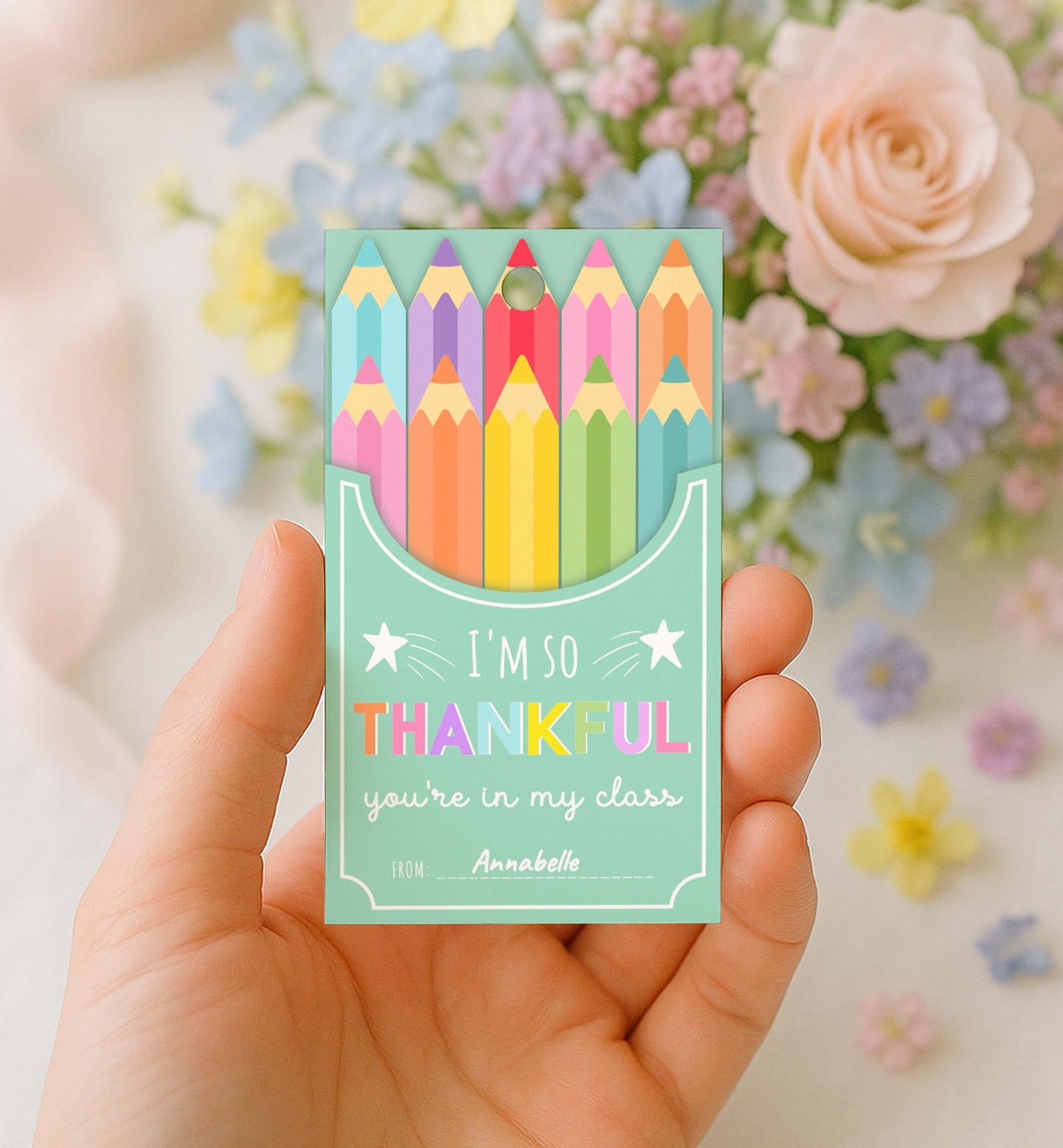 Card with colorful pencils and text held in a hand with flowers in the background. Printable Back To School Tag Template, I'm So Thankful You're In My Class Pencil Holder Tag, New School Year Classroom Gift, Crayon Gift