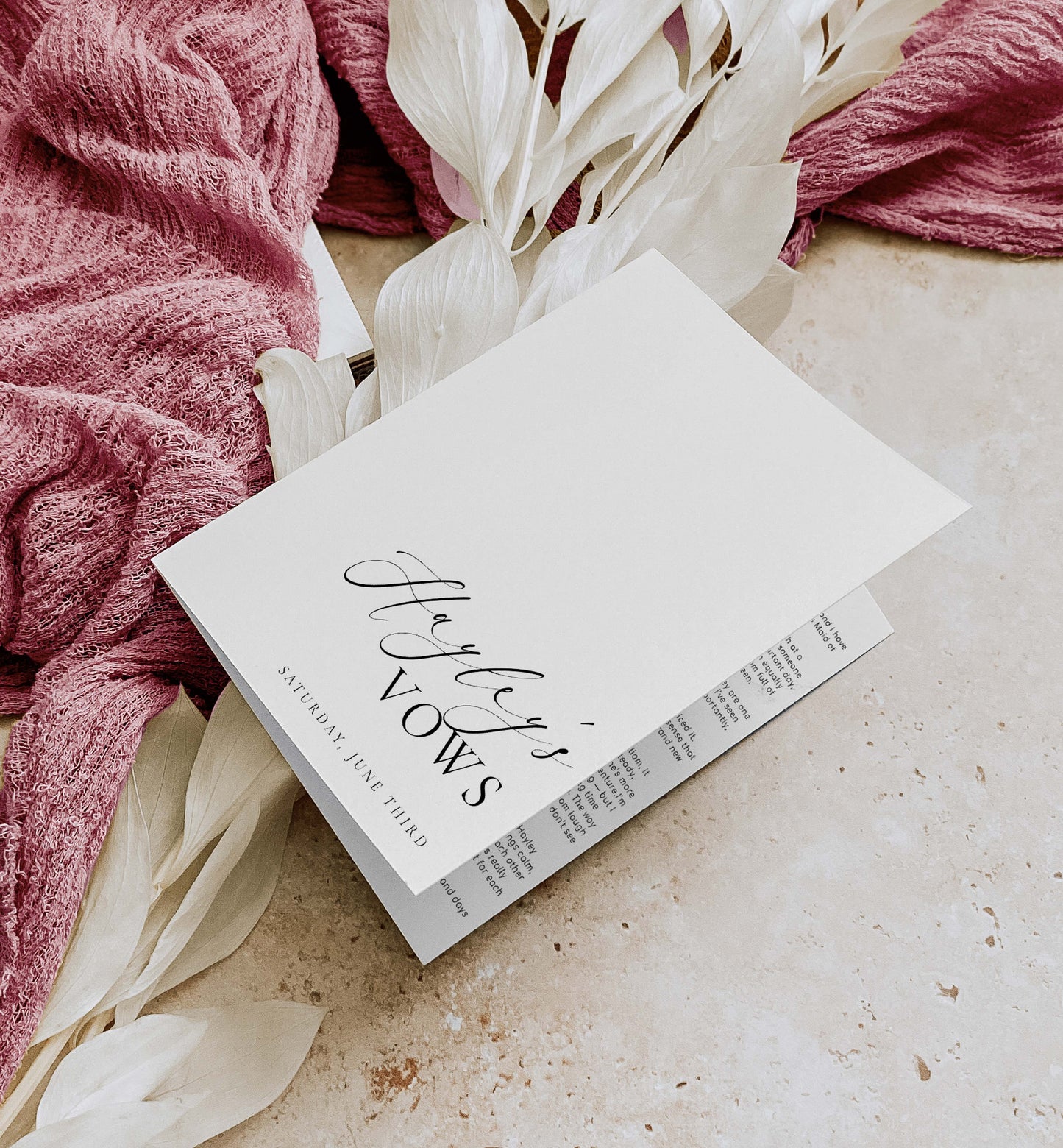 Book titled 'Hayley's Vows' on a surface with pink fabric and white flowers. Printable His And Her Vow Books, Bride and Groom Wedding Day Card Template, Minimalist Wedding Vows Card, Wedding Ceremony Card Ellesmere
