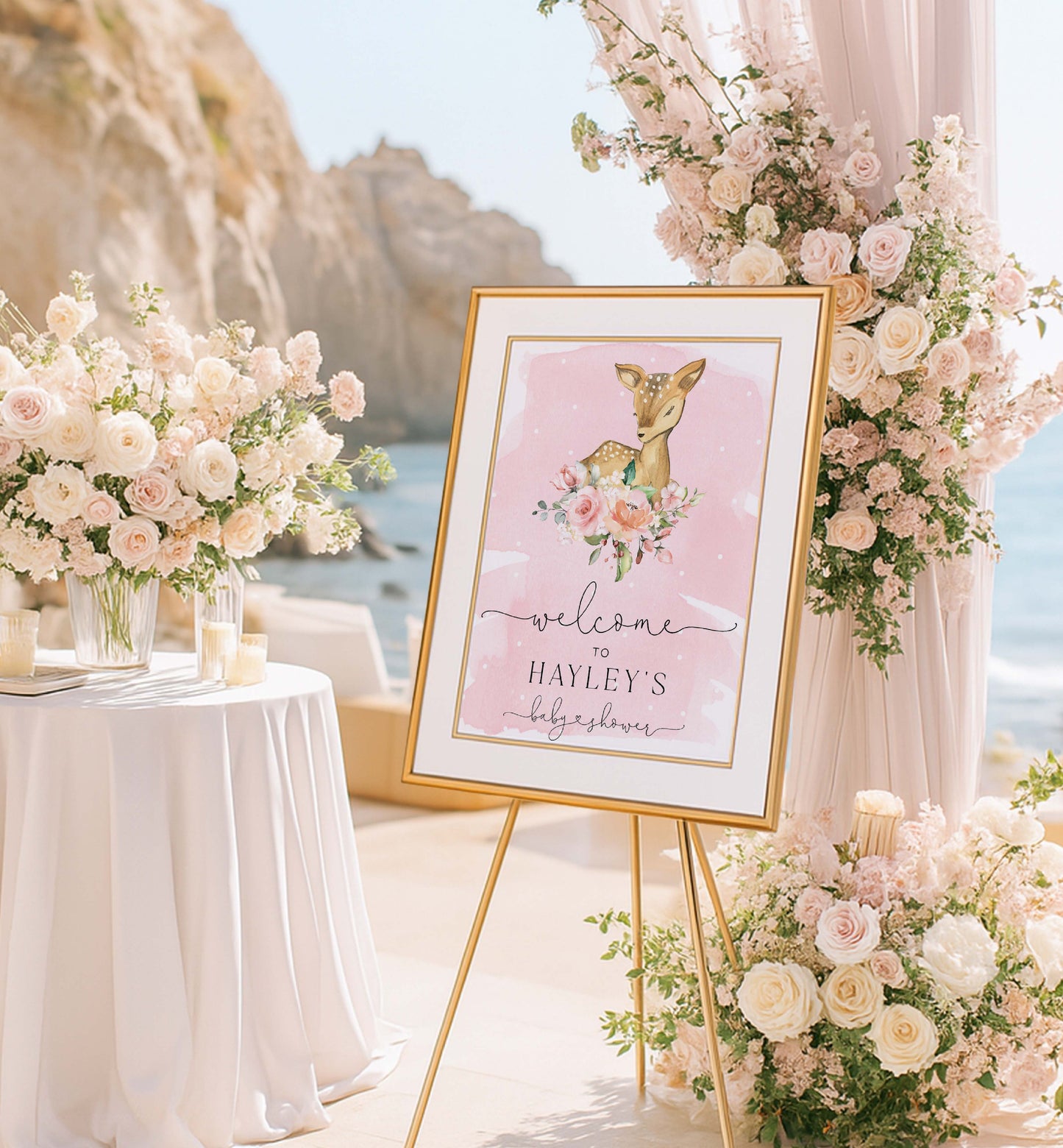 Decorative sign with a deer illustration and 'welcome' text, surrounded by floral arrangements on a beach. Printable Welcome Sign, Oh Deer Baby Shower Welcome Sign, Woodland Animals Girl Baby Shower, Oh Deer A Baby Girl Is Almost Here, Pink