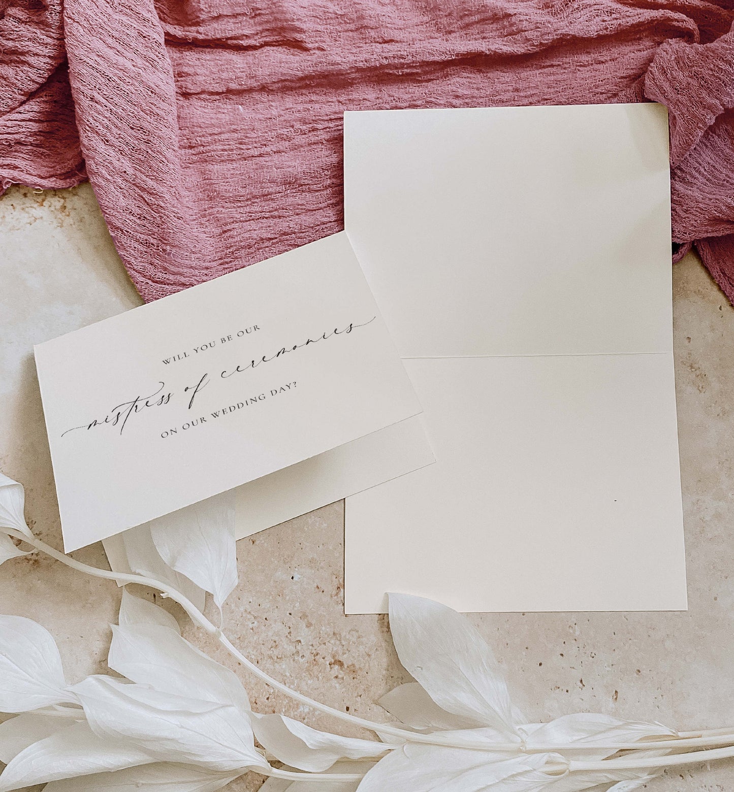Invitation card with envelope on a textured surface with pink fabric and white flowers. Will You Be Our Mistress of Ceremonies Card, Wedding MC Proposal Card, Minimalist Wedding Card, Wedding Proposal Card, Off White, Ellesmere
