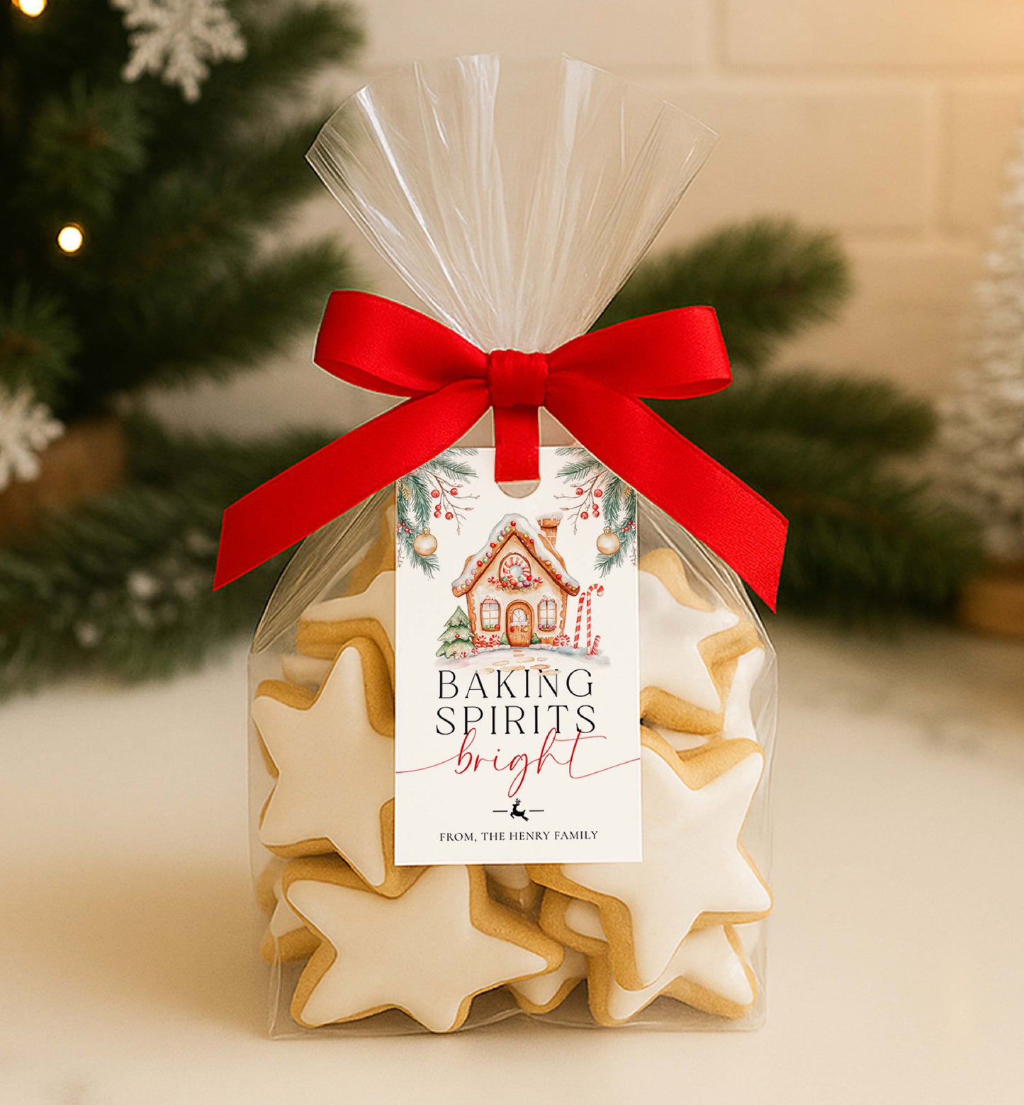 Packaged star-shaped cookies with a red ribbon and Christmas-themed label in front of a decorated tree. Printable Baking Spirits Bright Gift Tag, Gingerbread House Gift Label, Custom Gift Label Tag, Homemade Christmas Gift Wrapping Tag