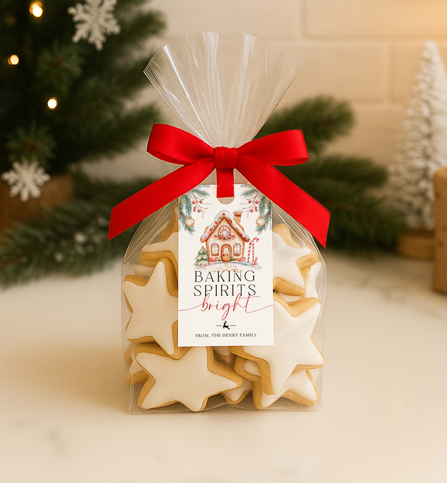 Packaged star-shaped cookies with a red ribbon and Christmas-themed label in front of a decorated Christmas tree. Printable Baking Spirits Bright Gift Tag, Gingerbread House Gift Label, Custom Gift Label Tag, Homemade Christmas Gift Wrapping Tag