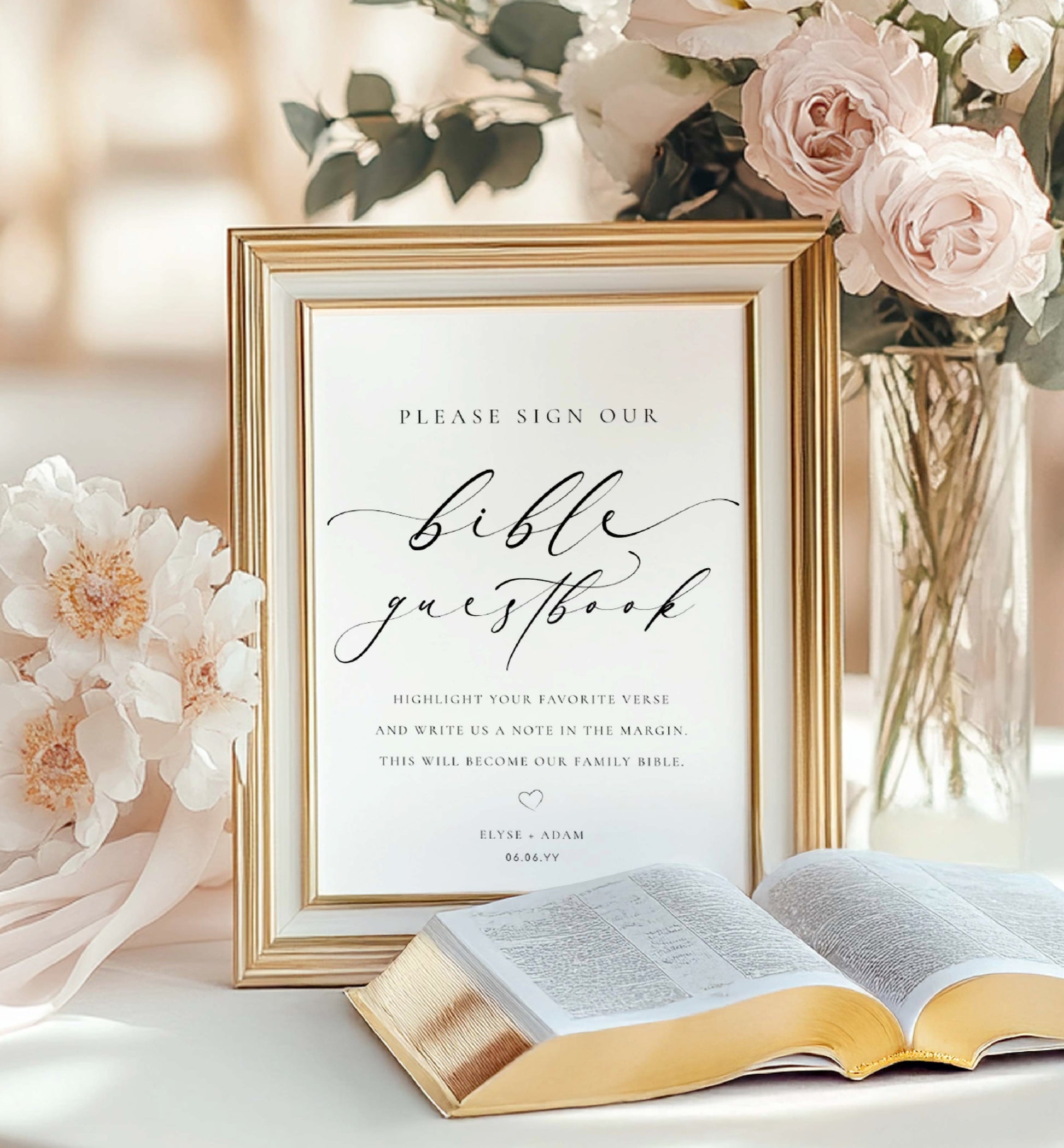 Framed wedding guestbook sign with an open Bible on a table with flowers.