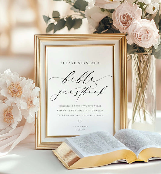 Framed wedding guestbook sign with an open Bible on a table with flowers.