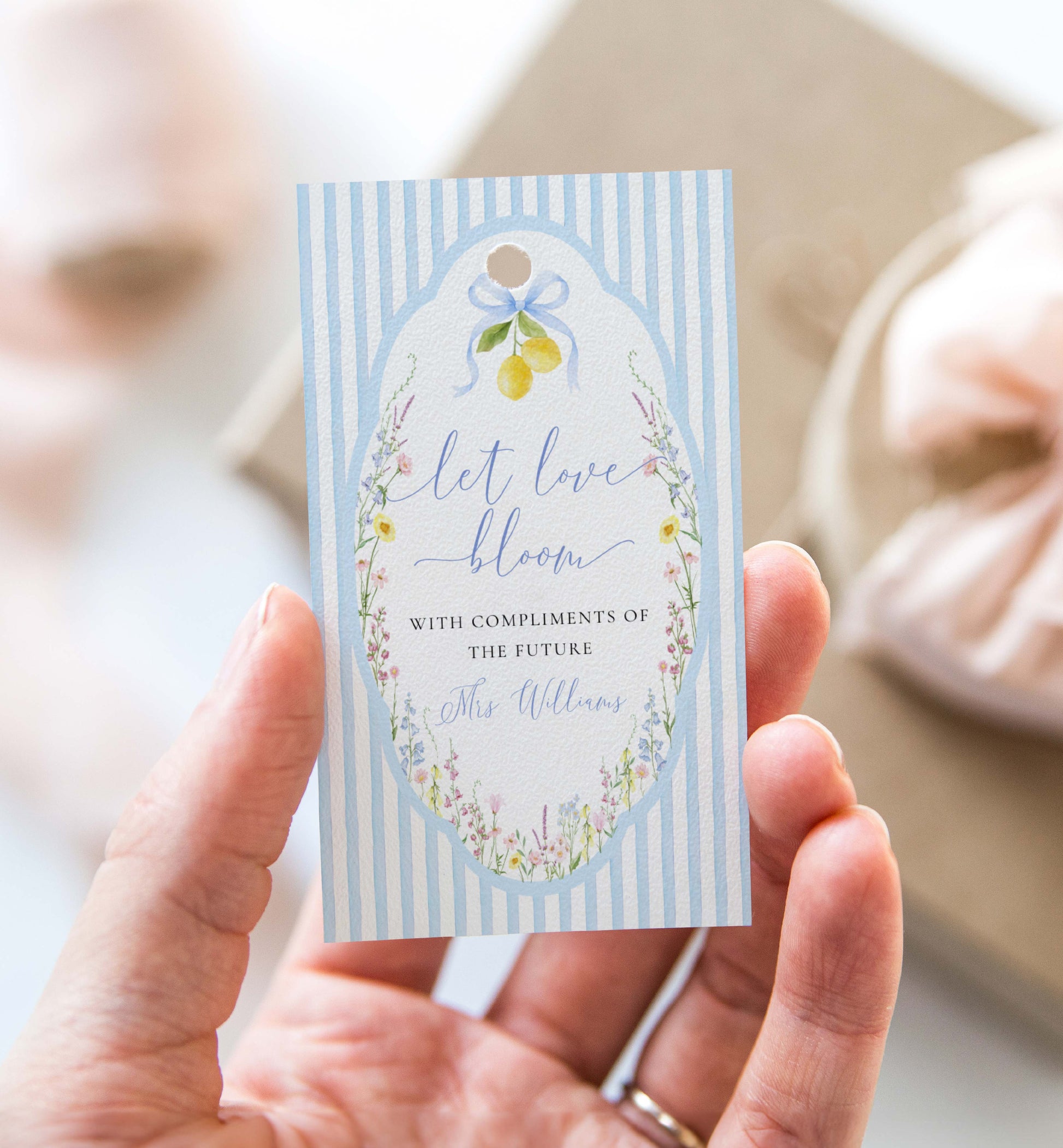 Hand holding a decorative card with floral design and text. Printable Bouquet Bar Sign, Spring Wildflower, Blue Bow Bridal Shower Bouquet Station Favor Sign, Posey