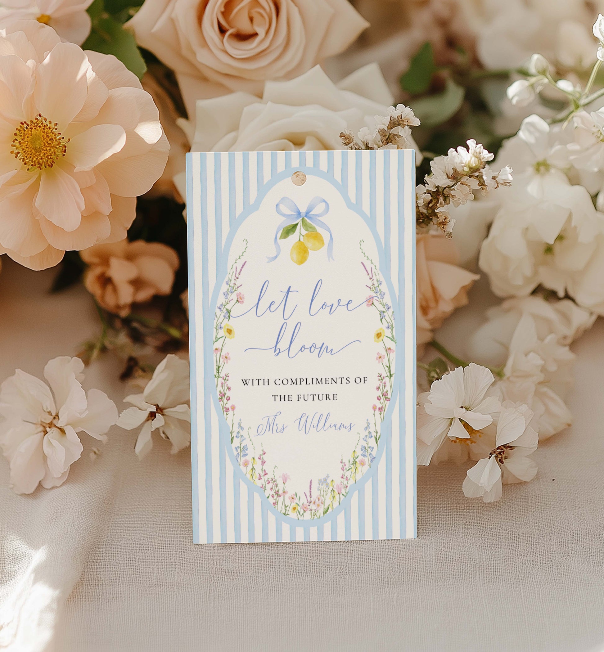 Gift tag with floral design and text 'Let love bloom' on a background of flowers. Printable Bouquet Bar Sign, Spring Wildflower, Blue Bow Bridal Shower Bouquet Station Favor Sign, Posey