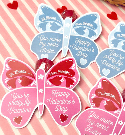 Butterfly-shaped Valentine's Day cards on a pink and white striped background with hearts. Butterfly Valentine's Day Lollipop Tags Template, Printable You Make My Heart Flutter Lollipop Tag, Pretty Fly Sucker Tag, Kids Valentines