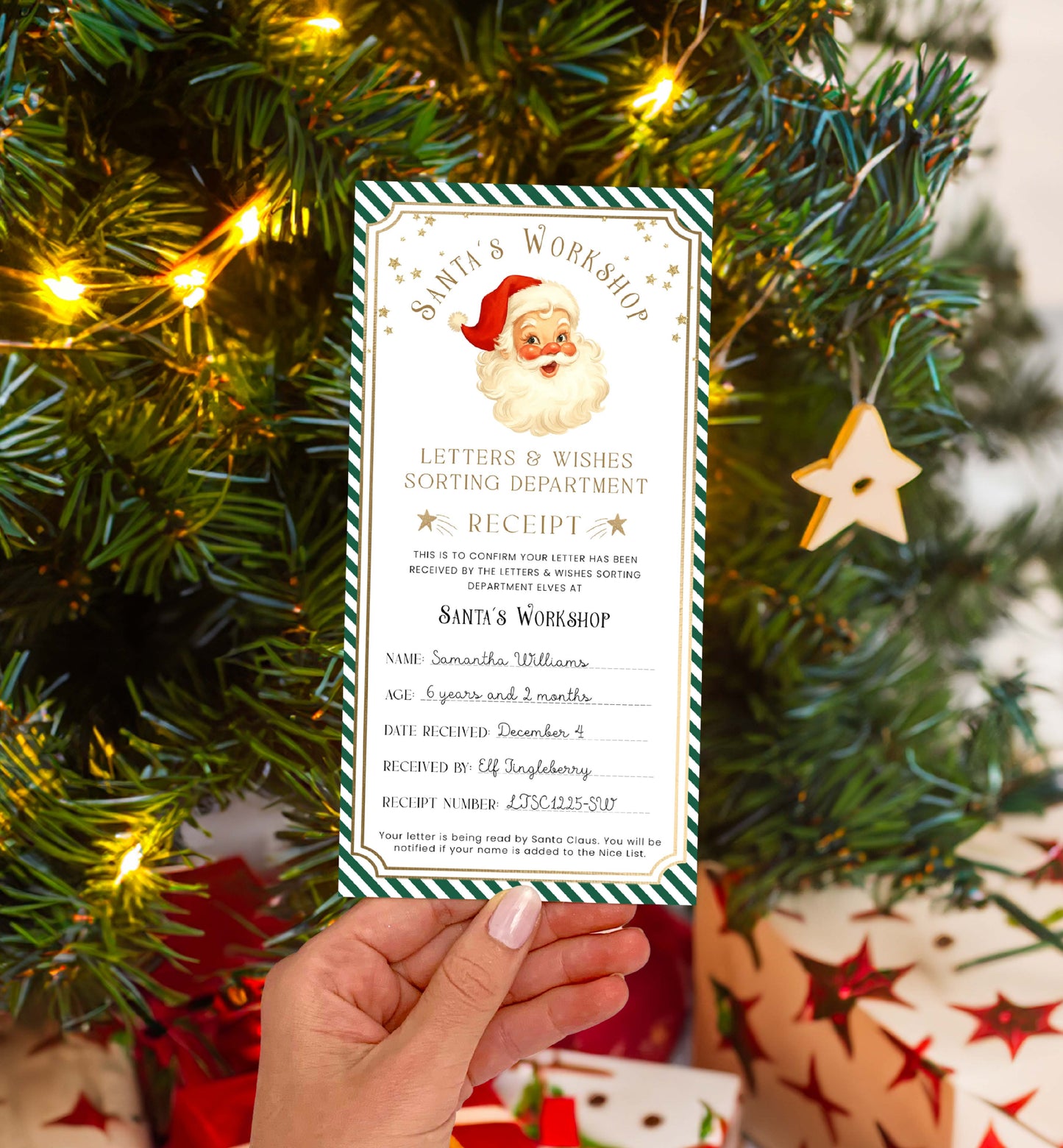 Hand holding a Santa Claus receipt card in front of a decorated Christmas tree with lights and presents. Printable Letter To Santa Receipt, Santa's Nice List Receipt, Letter From Santa's Workshop, North Pole Mail, Christmas Eve Box Santa Letter