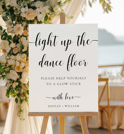 Decorative sign with floral arrangement on a stand at a wedding reception. Printable Wedding Glow Stick Sign, Minimalist Wedding Light Up The Dance Floor Sign, Editable Let Love Glow Sign Template, Leyton