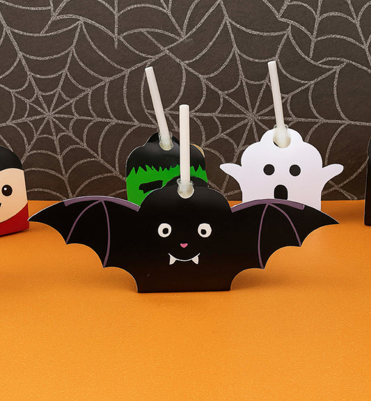 Halloween-themed cupcake toppers including a bat, ghost, and Frankenstein on an orange surface with a spiderweb background. Printable Halloween Lollipop Tags Template, Halloween Trick or Treat Sucker Tag, Kids Classroom Halloween, Friends Halloween Gift