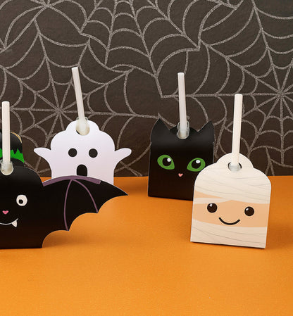 Halloween-themed candle holders shaped like a bat, ghost, and mummy on an orange surface with a spiderweb background. Printable Halloween Lollipop Tags Template, Halloween Trick or Treat Sucker Tag, Kids Classroom Halloween, Friends Halloween Gift