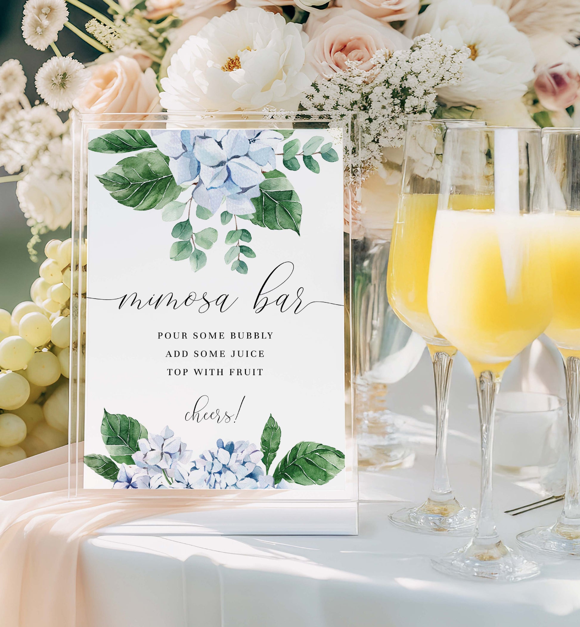 Mimosa bar setup with floral decorations and champagne glasses. Printable Mimosa Bar Sign and Juice Tags Template, Blue Hydrangea Boy Baby Shower Drinks Bar Menu Sign, Gender Neutral, Ferras Blossom