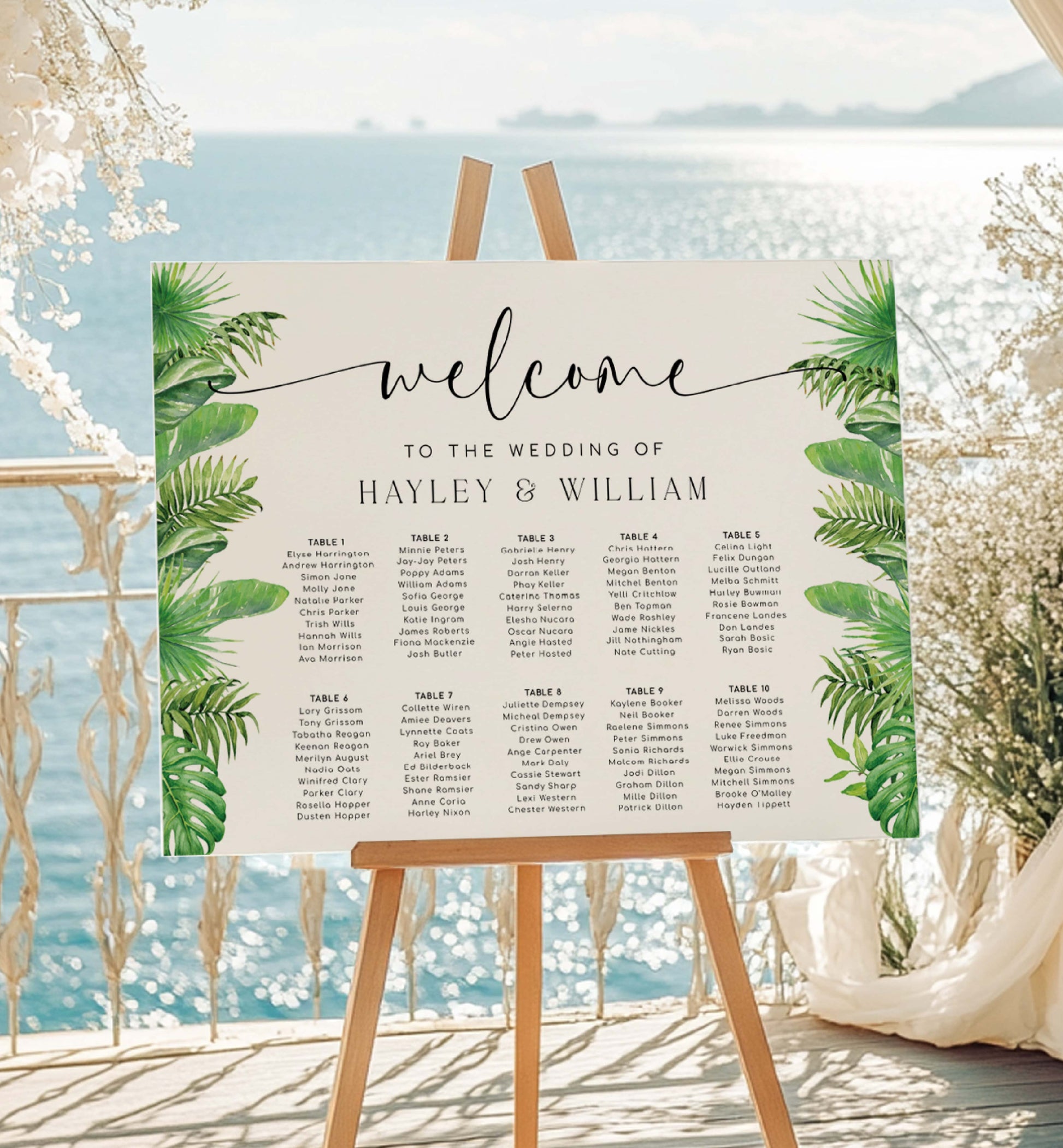 Wedding seating chart with tropical leaf design on an easel by a beach. Tropical Palm Wedding Table Plan, Printable Editable Seating Chart Template, Tropical Greenery Wedding Seating Plan Card, Nantucket Palm