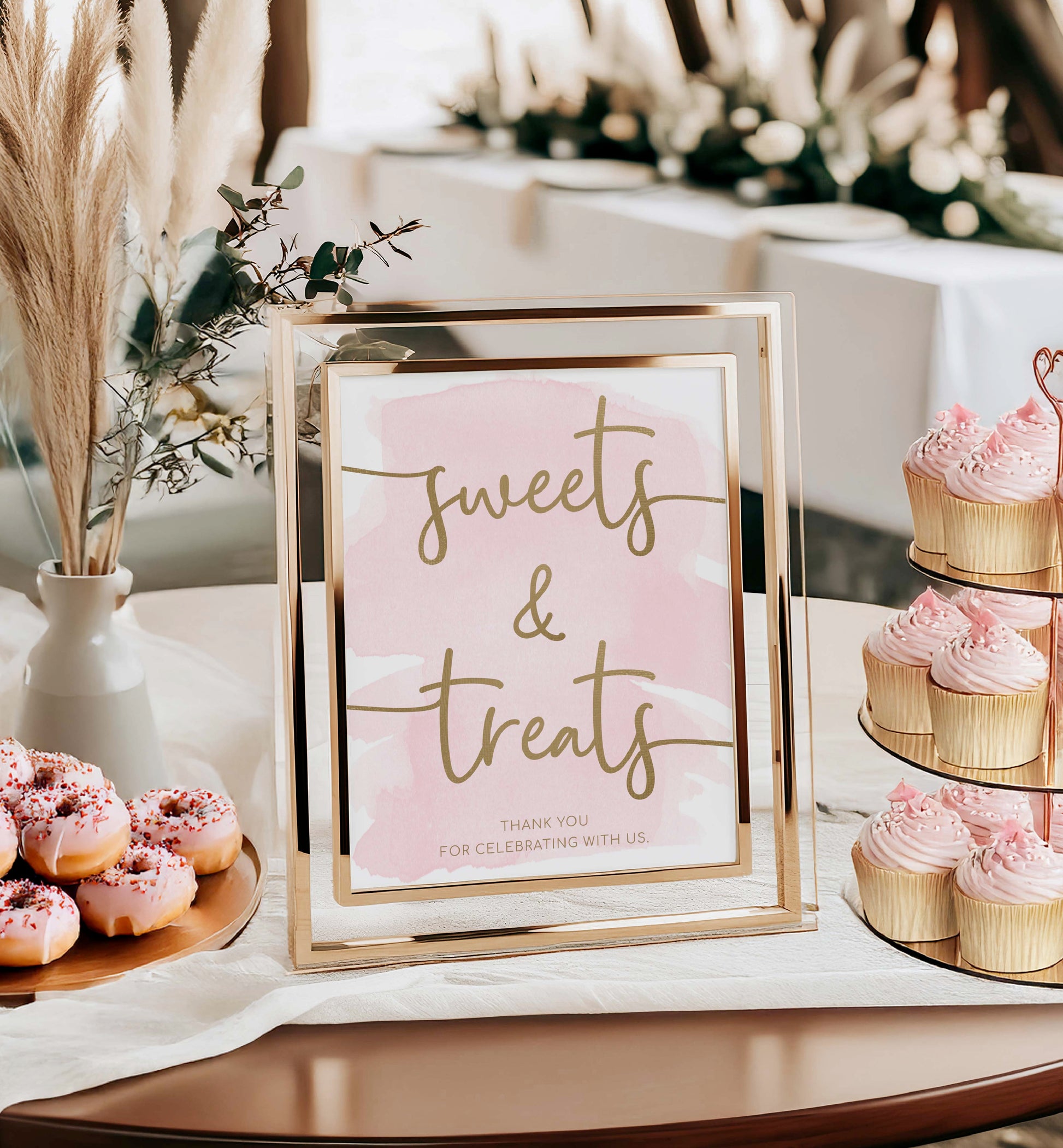 Decorative sign with 'sweets & treats' text in a gold frame, surrounded by pink donuts and cupcakes on a table. Sweets and Treats Favors Sign, Pink Watercolour Printable Favours Sign, Gold Foil, Bridal and Baby Favors Shower Sign, Wedding Favors Sign