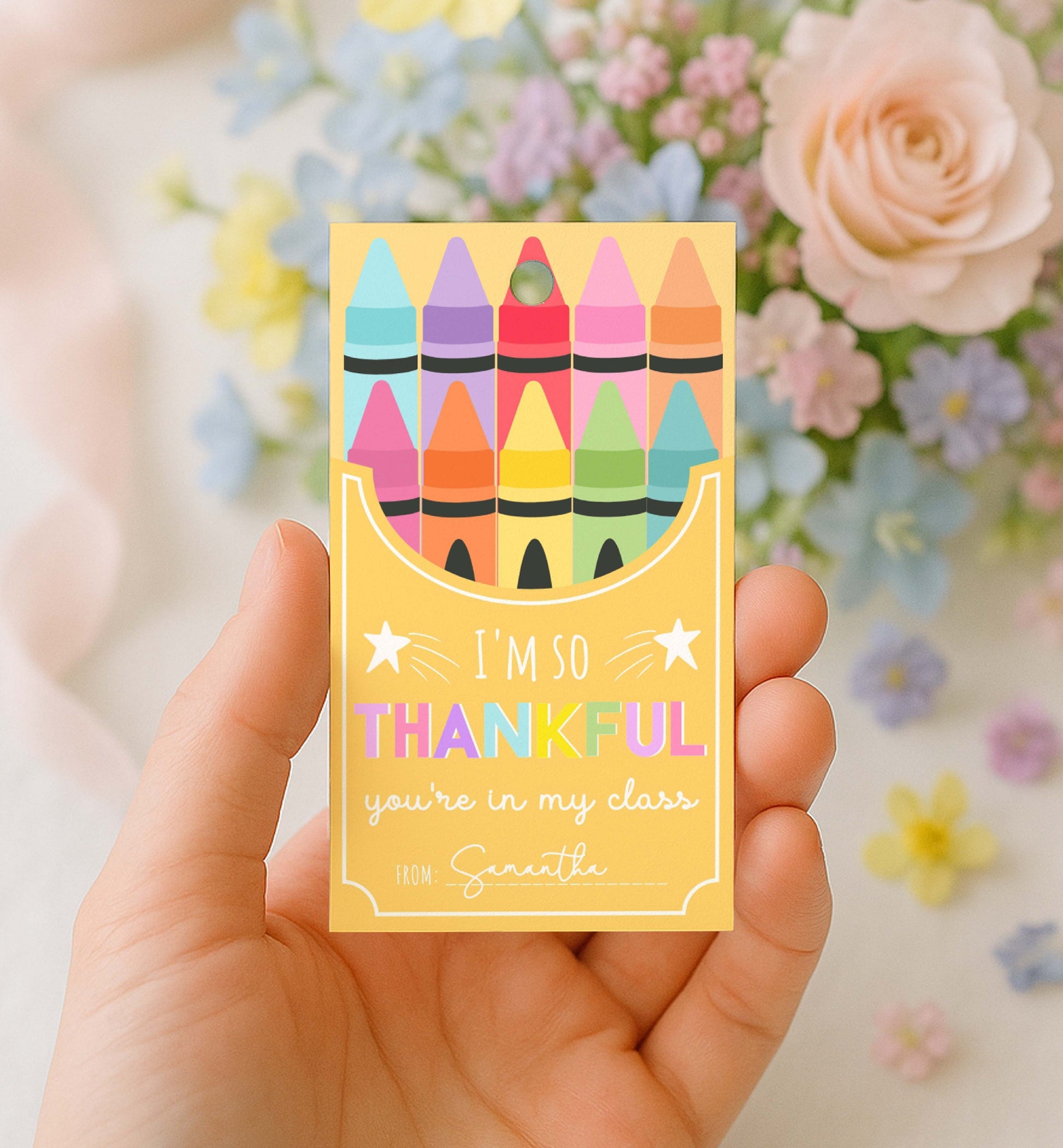 Hand holding a card with colorful crayon design and text in front of flowers. Printable Back To School Tag Template, I'm So Thankful You're In My Class Pencil Holder Tag, New School Year Classroom Gift, Crayon Gift
