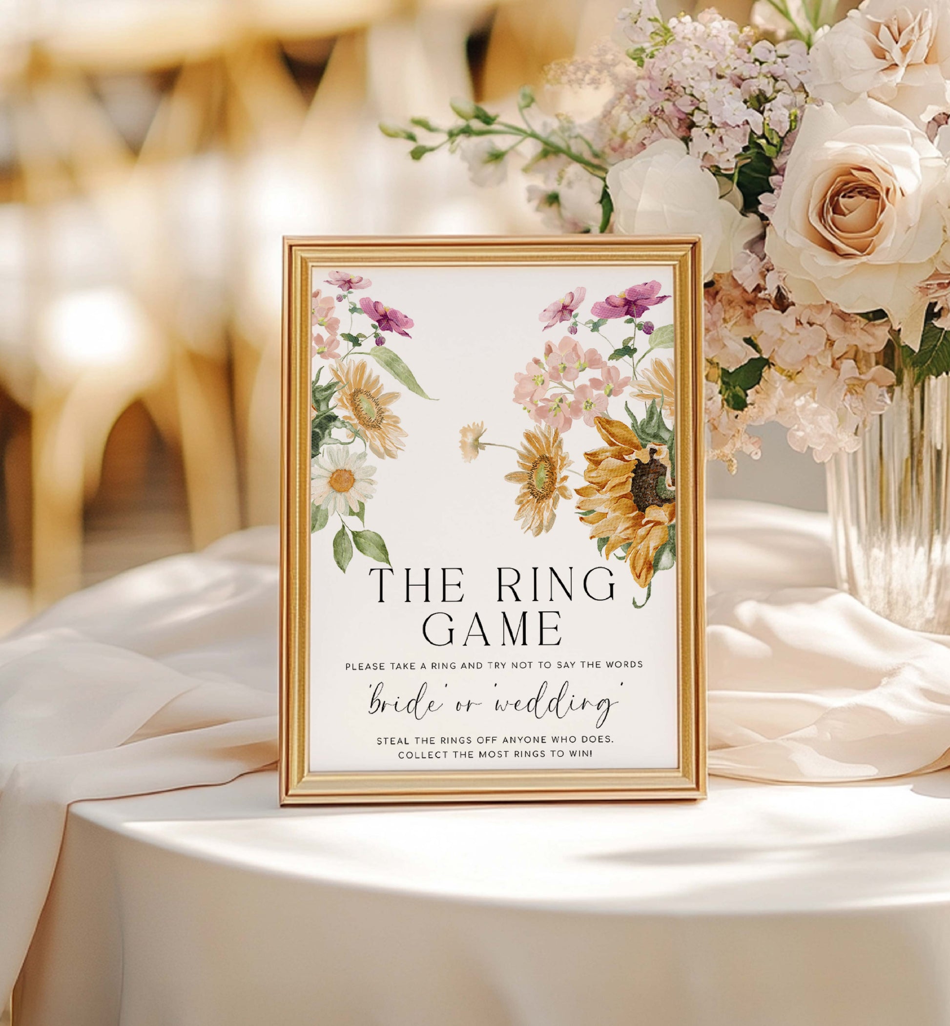 Framed wedding sign with floral design on a table with flowers in the background. The Ring Game Sign, Printable Don't Say Bride or Wedding Game Sign, Autumn Fall Sunflower Bridal Shower Game Sign, Mews