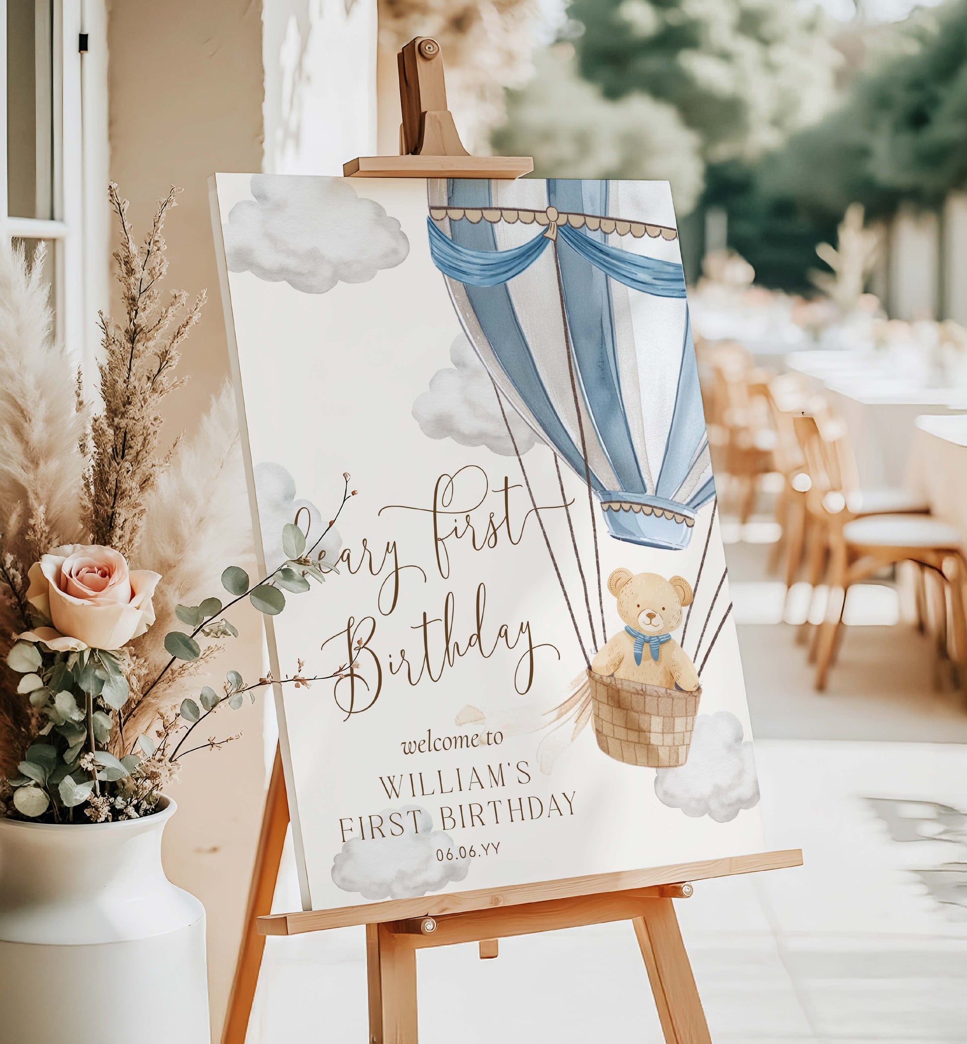 Birthday sign with hot air balloon and teddy bear on an easel, surrounded by flowers and outdoor setting. Printable Teddy Bear Welcome Sign Template, Beary First Birthday Welcome Sign, Blue Hot Air Balloon 1st Birthday Welcome Sign