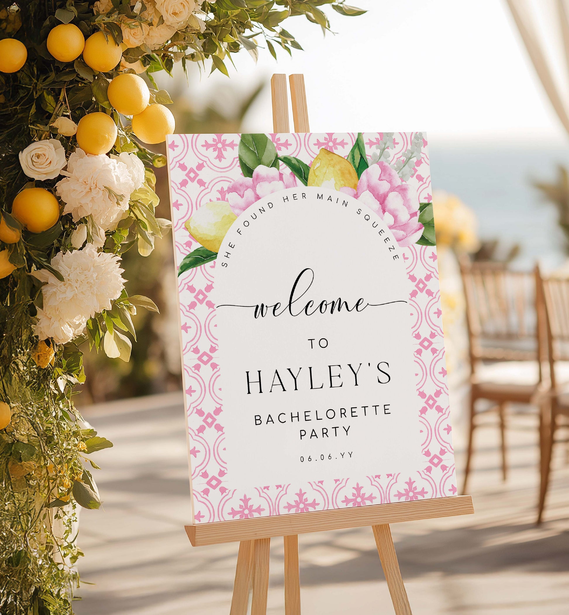 Bachelorette party welcome sign with floral design on an easel, surrounded by flowers and lemons.