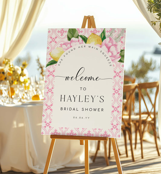 Welcome sign for Hayley's bridal shower with floral design on an easel outdoors.