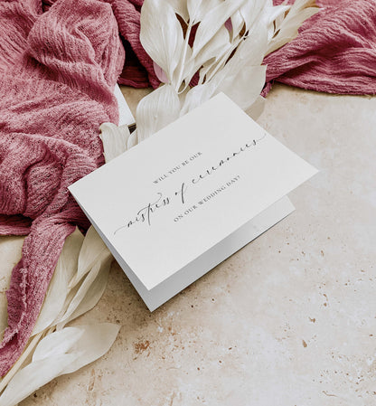 White card with wedding invitation text on a textured surface with pink fabric and white flowers. Will You Be Our Mistress of Ceremonies Card, Wedding MC Proposal Card, Minimalist Wedding Card, Wedding Proposal Card, Off White, Ellesmere